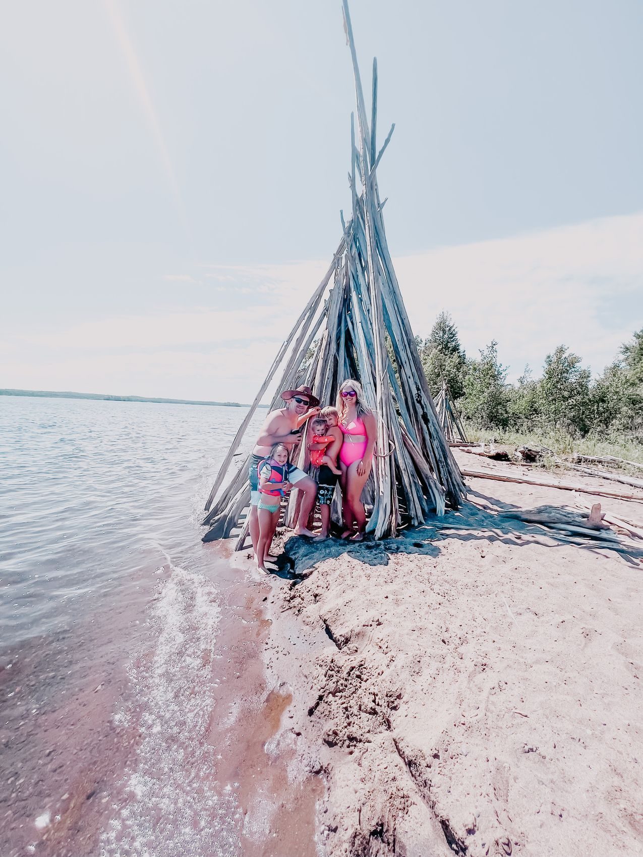Our family at a driftwood shelter on a lake beach