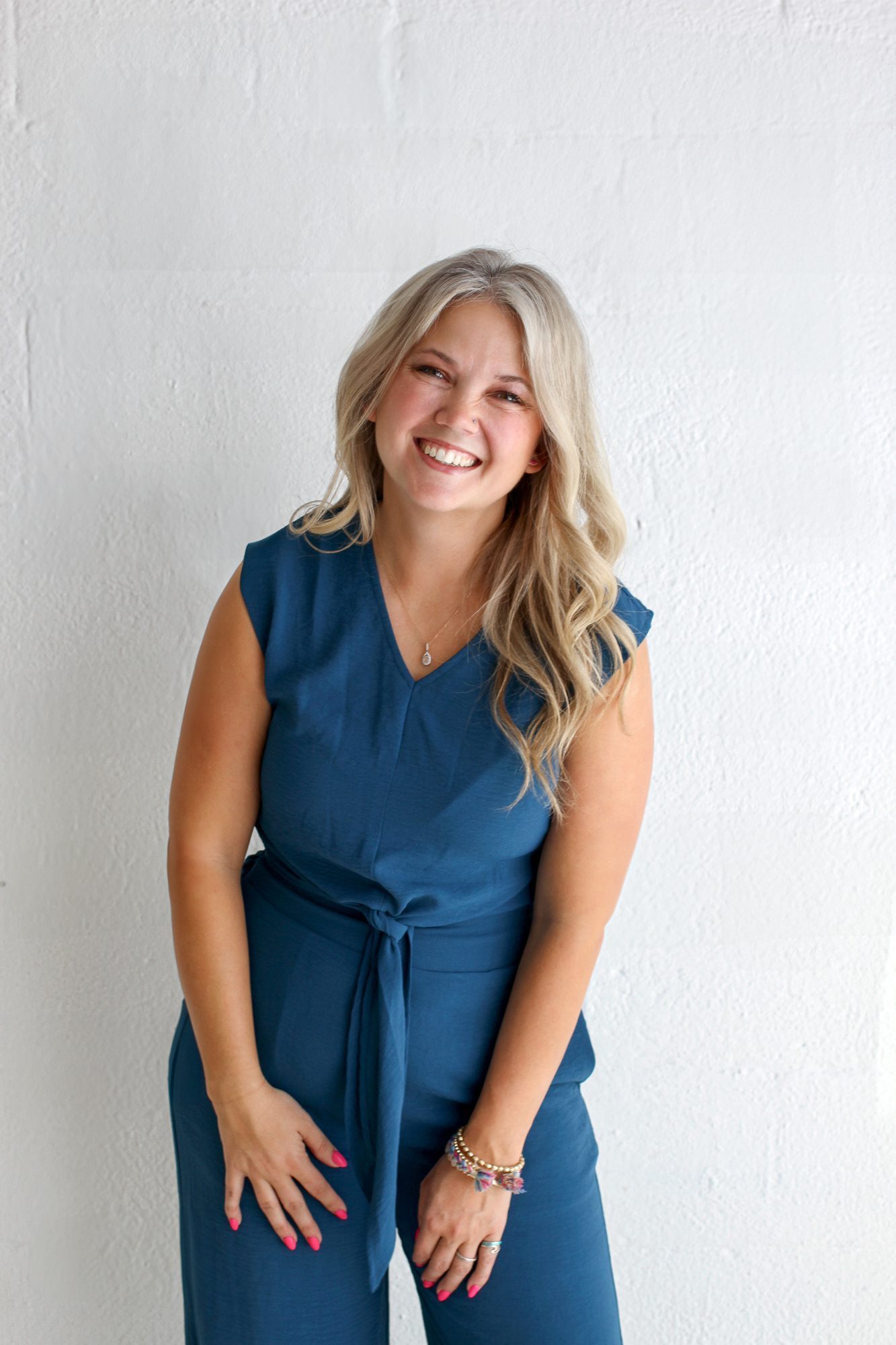 Samantha laughing in a teal jumpsuit