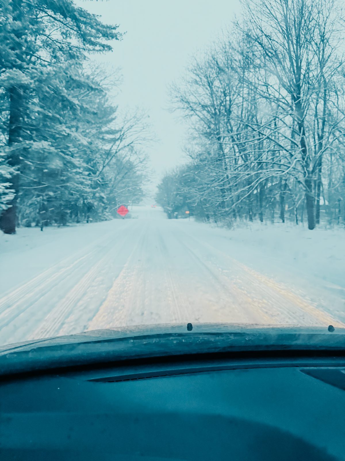 A snow covered road seen through a windshield